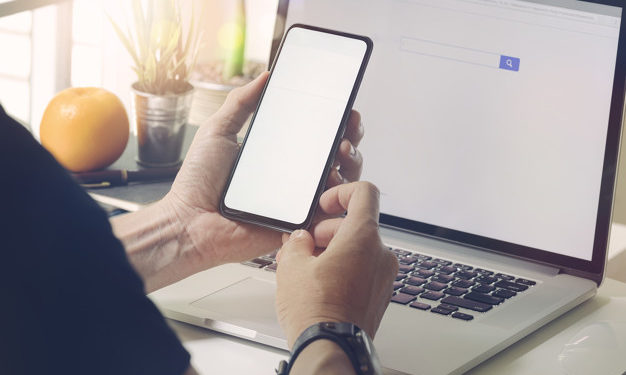Man sitting at office desk and using the mobile smartphone.